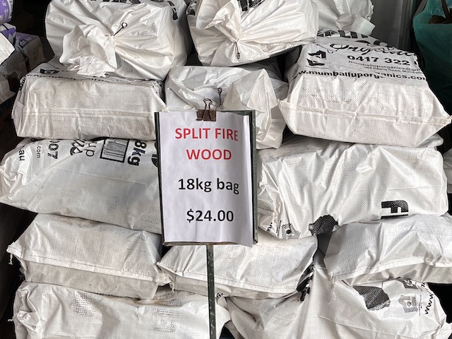Bagged split fire wood with a price sign saying $24 for an 18kg bag